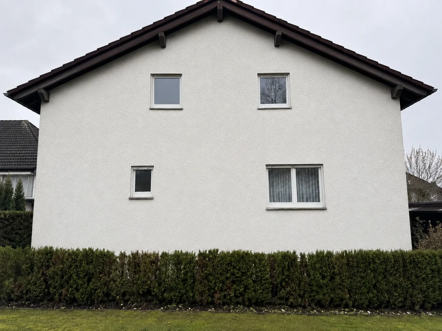 Dieselbe Wohnhausfassade nach der Reinigung, gleichmäßig sauberer heller Putz