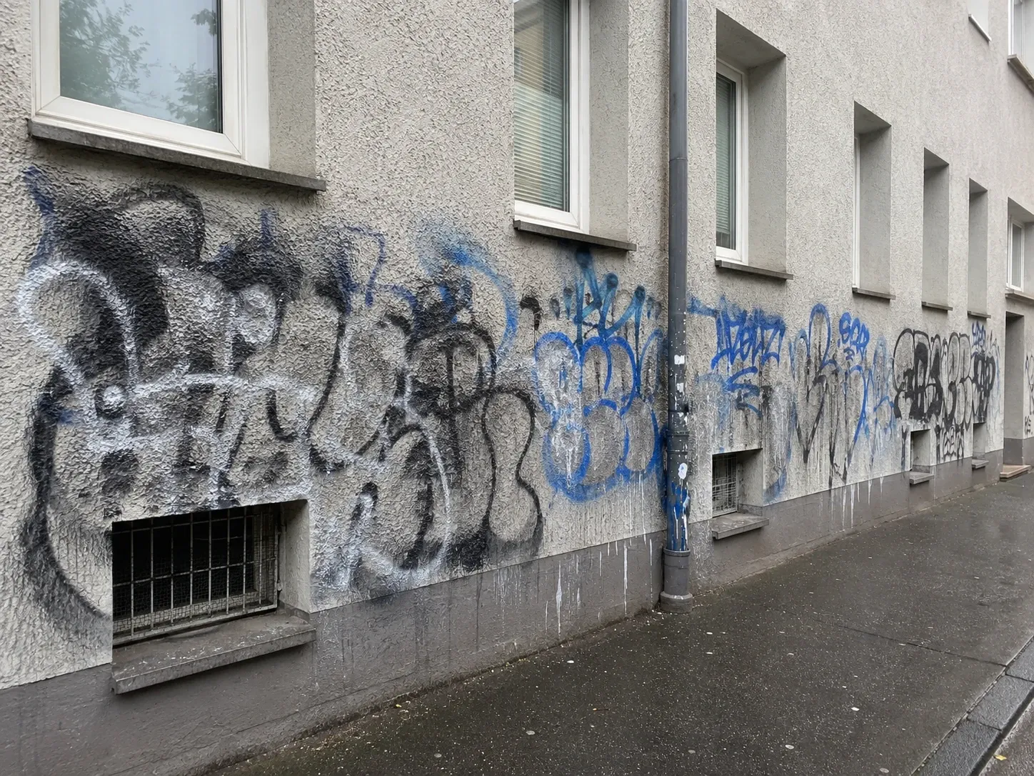 Straßenfassade mit großflächigem Graffiti an der Sockelzone, vor der Entfernung